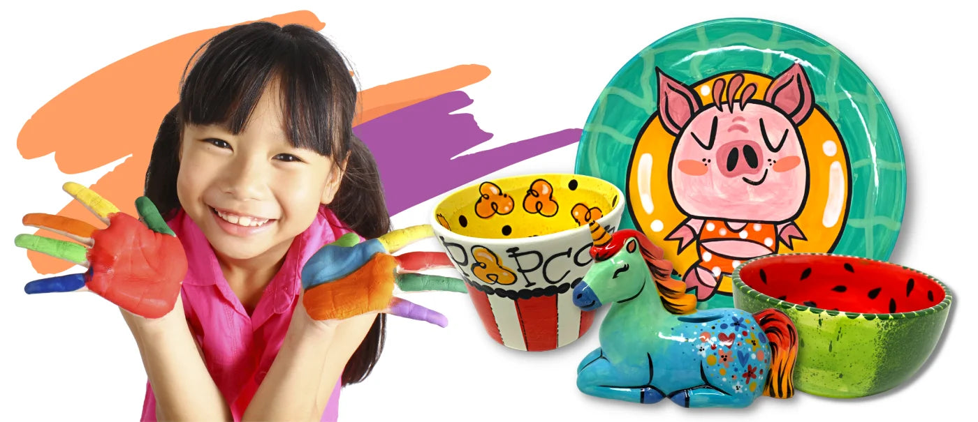 Asian little girl with paint on her hands, and two painted bowls, one with a unicorn sculpture and another plate with a pig design.