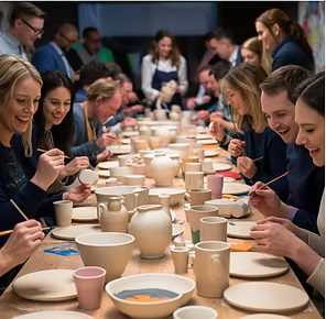 A corporate team-building event with about 20 people painting pottery together, fostering creativity and collaboration at Color Café.